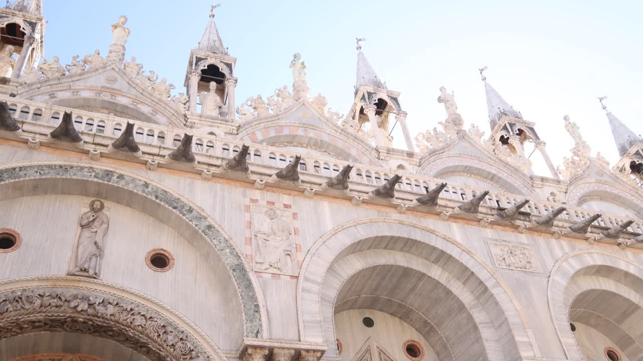 Facade of St. Mark's Basilica in Venice on a bright day with intricate stone details and sculptures