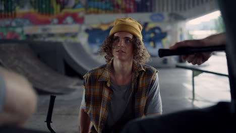 Young-people-talking-together-at-skate-park-graffiti.-Teens-resting-outdoors.