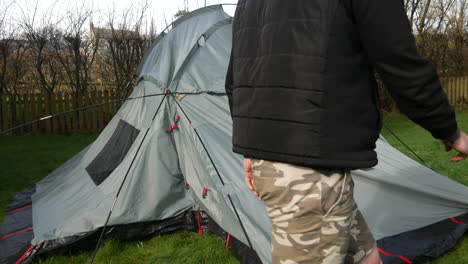 A-man-taking-down-and-dismantling-a-tent-at-high-speed-in-a-field-after-camping-at-a-campsite