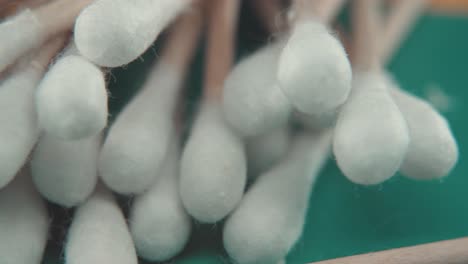 a smooth detailed macro pan right shot of a pile of q tips, white soft cotton tips, brown wooden sticks, professional studio lighting, 4k video