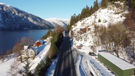 aerial over highway e16 between bergen and voss in norway. winter and traffic overtaking drone driving destination voss. - panoramic view over fjord, road and mountains