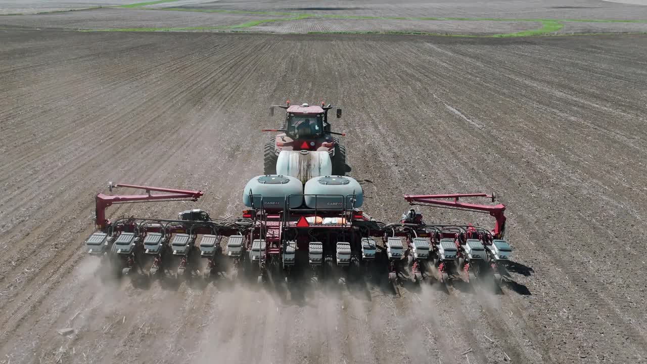 Drone footage of a farmer planting corn seeds in an iowa field in a red tractorDrone footage of a farmer planting corn seeds in an iowa field in a red tractor