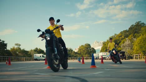 two driving instructors in yellow t-shirts hone their skills in motorcycle maneuverability. two guys go around obstacles on a motorcycle