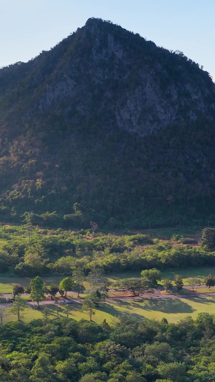 Imagens de drone capturam uma paisagem exuberante de floresta tropical sob uma montanha proeminente na Tailândia.