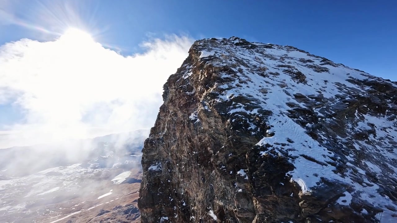 Volo drammatico con drone FPV che segue la cresta sommitale innevata del Cervino in Svizzera. Vedute aeree cinematografiche rivelano l'iconica vetta alpina, i ghiacciai e il terreno montuoso aspro.
