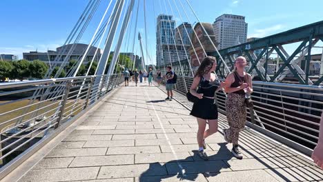 pedestrians crossing hungerford bridge in london