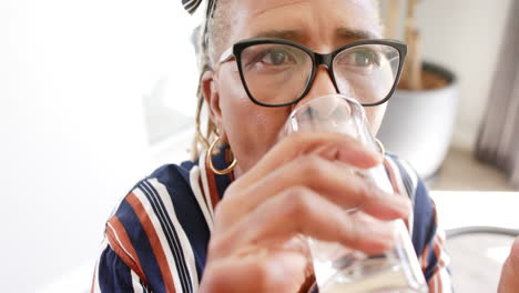 una anciana afroamericana con gafas está bebiendo agua