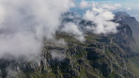 cloudscape rolling above majestic mountain range in south africa, aerial view