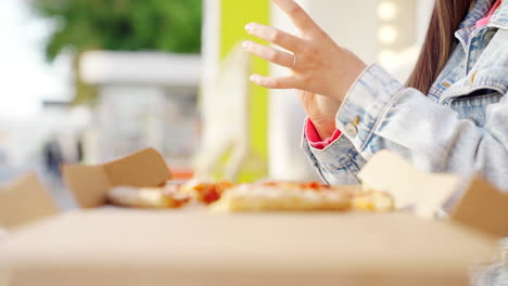 mujer comiendo pizza al aire libre