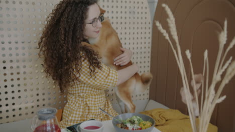 woman hugging shiba inu in a cafe