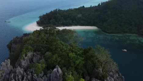 Beautiful-gray-rocks-covered-with-trees-while-in-the-background-traditional-Thai-boats-are-moored-on-the-white-sandy-beach-of-Ko-Poda-Beach-and-its-beautiful-clear-sea