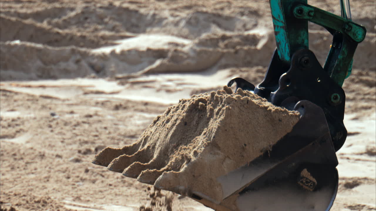 Close up of the wheels of an yellow loader spreading sand on the beach