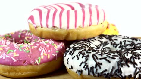 rotating donuts with different fillings on the table. delicious sweet donut rotating on a plate. bright and colorful donut close-up macro shot spinning on a white background. seamless loop.