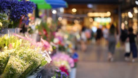 colorful flowers on display, people shopping around