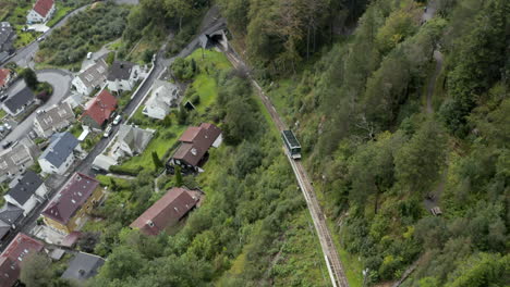 drone shot of one of the trains on the floibanen funicular ascending towards the summit of mount floyen