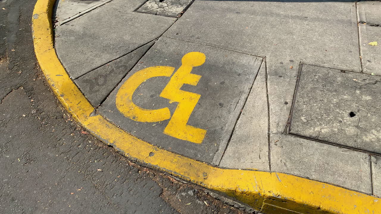 señal de discapacitados pintada de amarillo en el pavimento de la acera en la ciudad de méxico