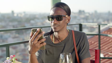 happy man sitting on rooftop terrace and having video call