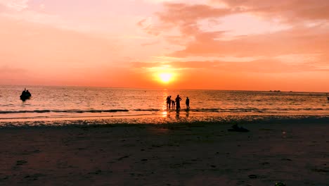 Siluetas-De-Personas-De-Pie-En-La-Playa-De-Sairee-Durante-La-Hora-Dorada-Del-Atardecer-En-Koh-Tao,-Tailandia