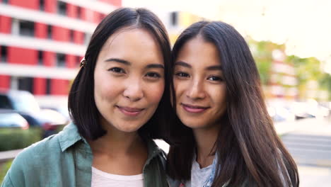 outdoor portrait of two beautiful young japanese girls looking and smiling at camera 1