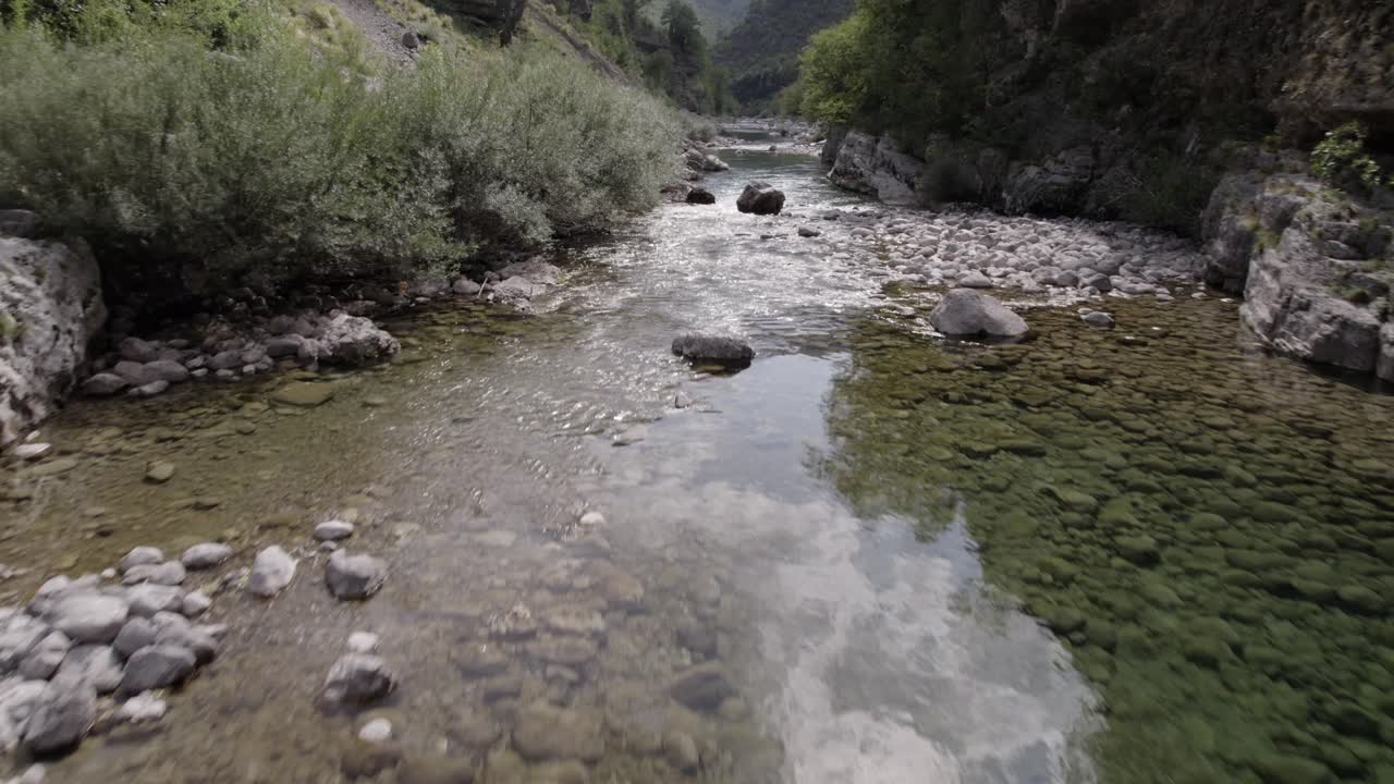 Drone video of ascending frontal plane advancing over the interior of the Cemi river on the Sh20 road between the mountains in Albania between Tamarë and Selcë, cloudy sky and turquoise river waters