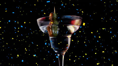 confetti animation over martini glass with olives on black background