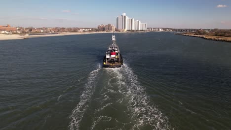 an aerial view of a tugboat on a sunny day in the east rockaway inlet in queens, ny