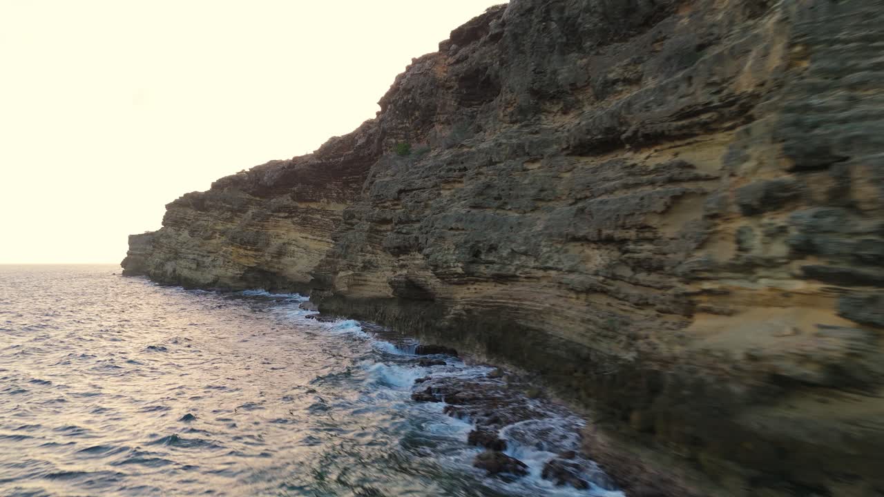 Vista aerea con drone di una scogliera costiera rocciosa a Caracasbaai al tramonto con una calda luce dorata.