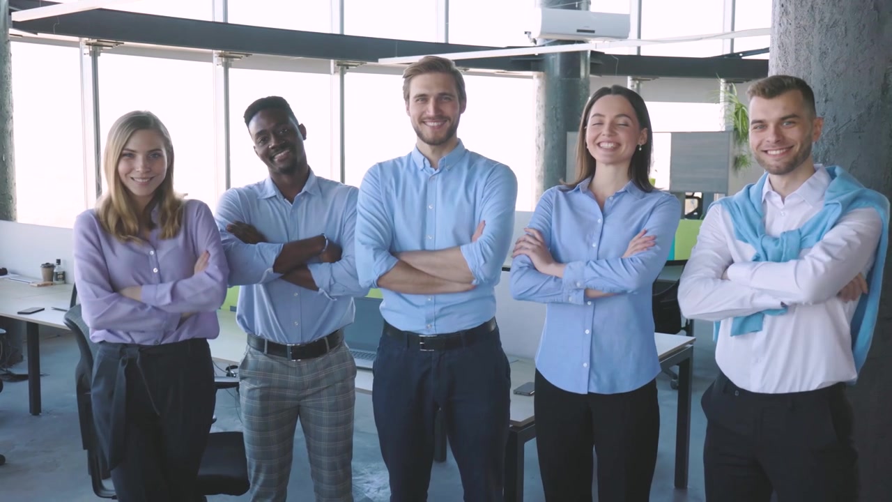 Selbstbewusstes Geschäftsteam steht mit verschränkten Armen im modernen Büro