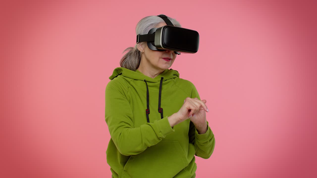 Anziana nonna elegante che usa un visore con app per giocare a un gioco di simulazione in realtà virtuale (VR).