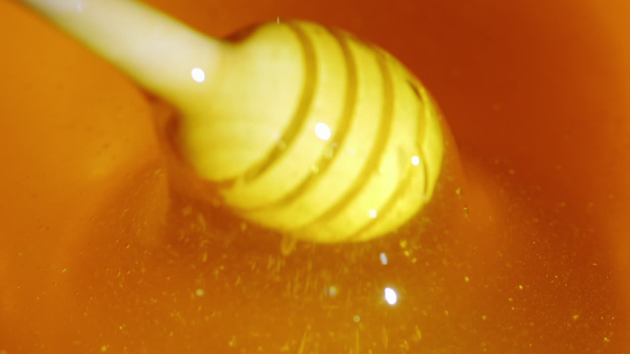 ハチミツからスプーンを取り除く 純粋な新鮮なハチミツ スローモーションビデオを下に流す