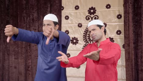 two muslim men showing thumbs down