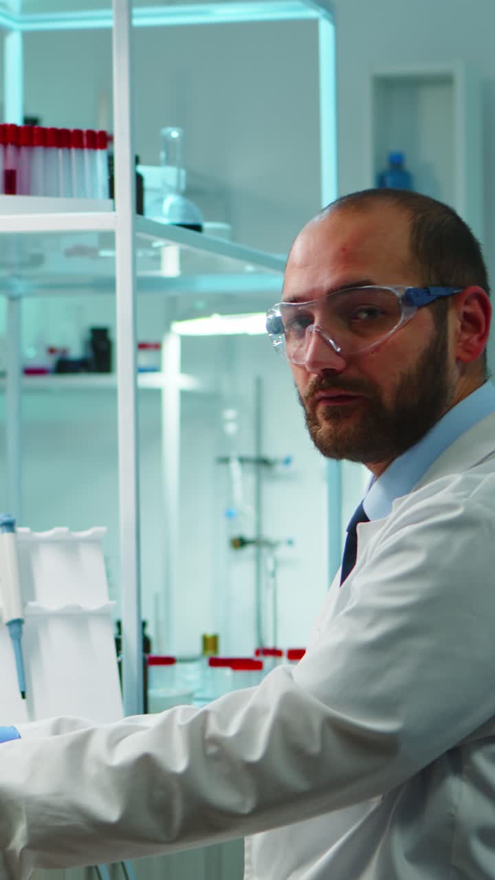 Vertical video: Worn out doctor typing on computer and looking exhausted at camera