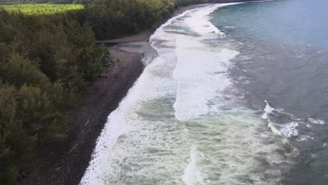 Drone-Revela-El-Valle-De-Waipi&#39;o-Desde-La-Playa-De-Arena-Negra-En-Medio-De-Fuertes-Olas-Y-Nubosidad-Parcial-En-La-Isla-Grande-De-Hawaii