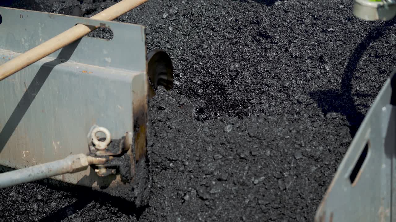 professional equipment with a mixer is blending a mix of rubble, tar, sand and bitumen for stowage asphalt on the highway. Manufacturing technology of asphalt concrete sweep for road works