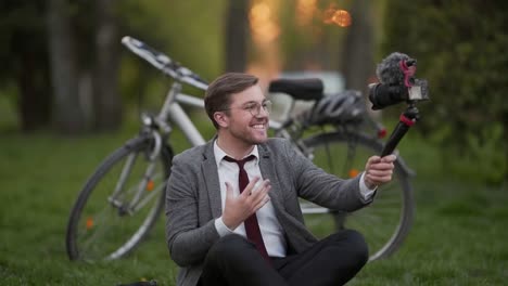 handsome young businessman shooting himself holding a tripod camera in his hands