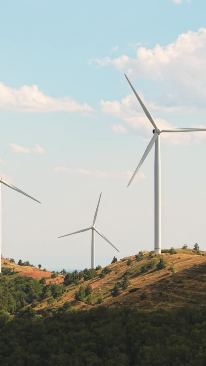 A calm yet powerful wind turbine rotating in a vertical scene with a brilliant cloudy sky. Renewable energy meets natural beauty