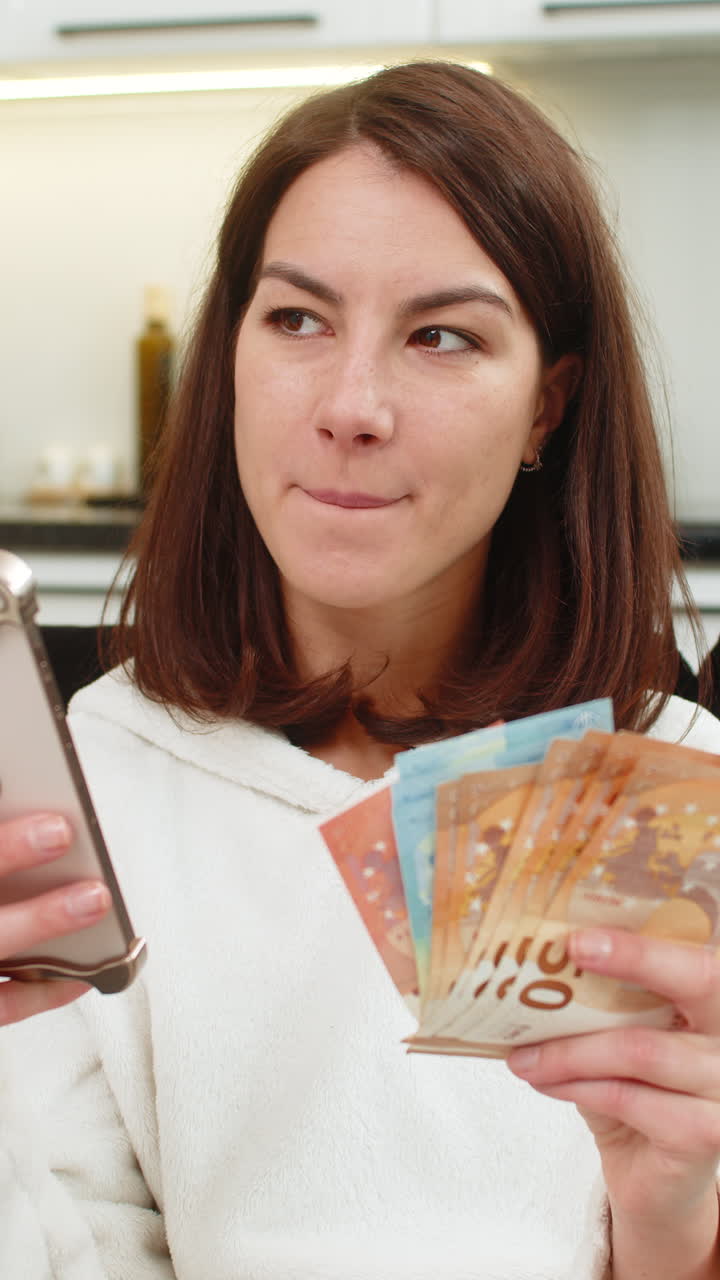 Donna conta euro in contanti, controlla il tasso sullo smartphone, sorride e pianifica di acquistare ciò che desidera con stipendio, risparmi e bonus