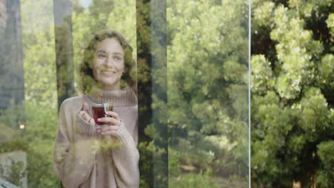 holding cup, woman smiling and relaxing by window, enjoying nature view, copy space