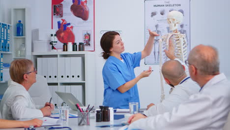 medical young nurse presenting spine anatomy with human skeleton model