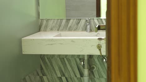 Mueble-Izquierdo-Que-Revela-El-Lavabo-De-Mármol-En-El-Baño-Con-Paredes-Verdes