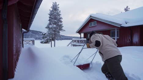 man using sleigh shovel to remove deep snow in indre fosen, norway - wide