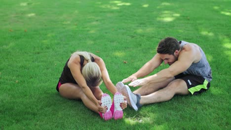 Ejercicio-De-Estiramiento-De-Entrenamiento-De-Pareja-Deportiva-Sobre-Hierba-Verde-En-El-Parque-De-Verano