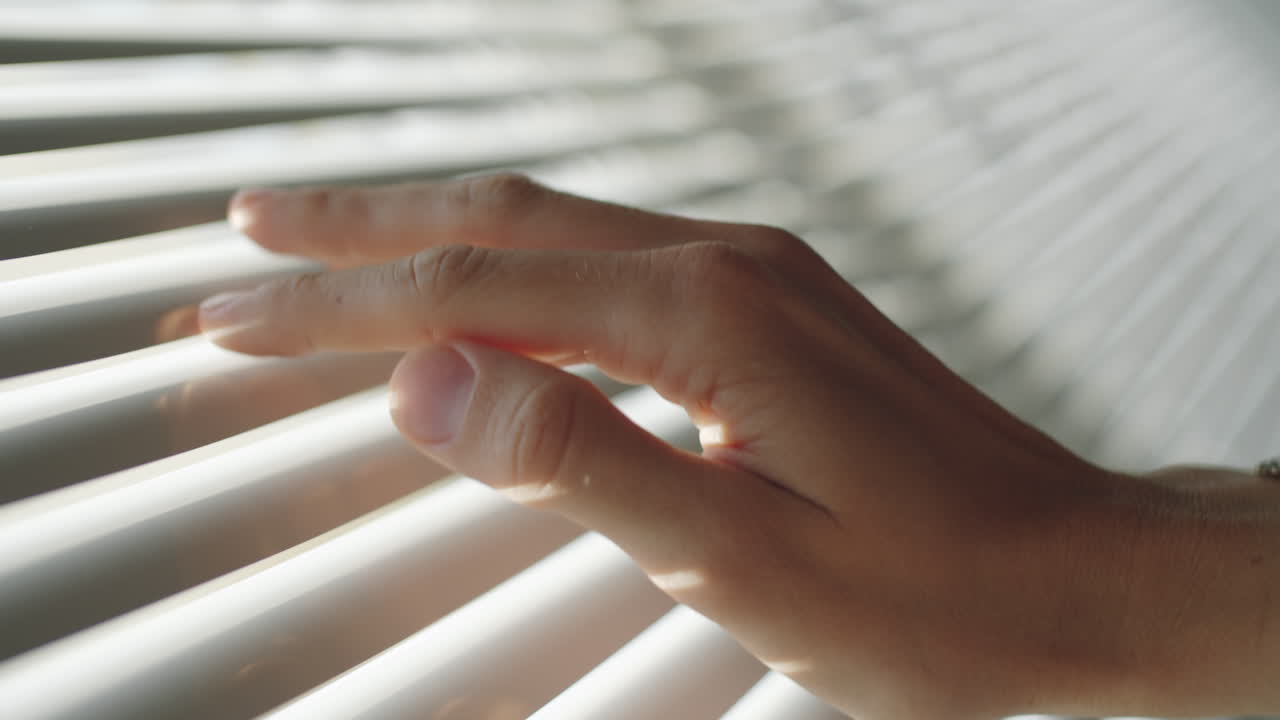 Hand Touching Window Blinds at Home