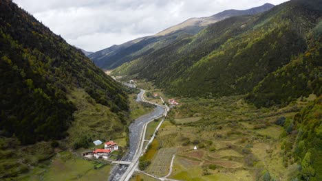 Epic-aerial-view-of-wide-river-cutting-down-in-valley-in-Tibetan-Sichuan,-China