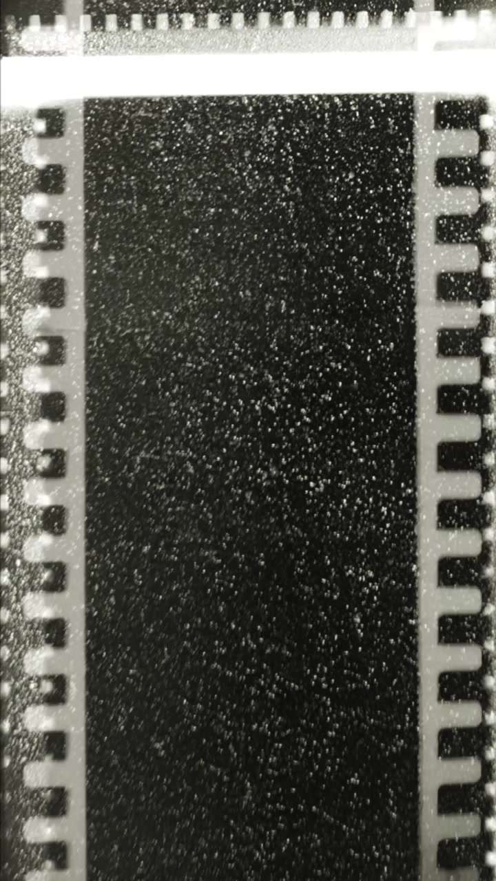 Primo piano di striscia di pellicola vintage in movimento con grana e perforazioni