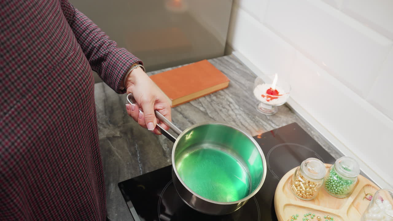 primer plano de una mujer girando una olla con sustancia verde, fondo con un libro marrón y una vela casi quemándose, proceso de cocción en la cocina con un enfoque detallado en la agitación y el manejo de la olla