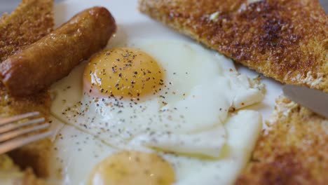 Close-up of English breakfast with fork and knife, natural lighting, shallow depth of field