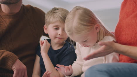 familia sonriente sentada en el sofá divirtiéndose usando una tableta digital juntos