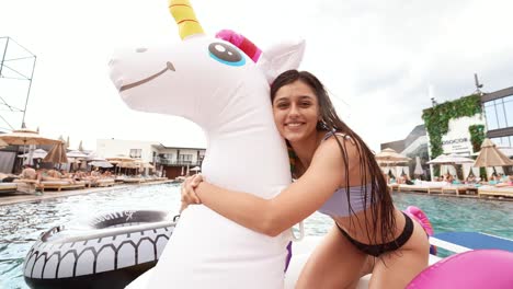 mujer abrazando un unicornio inflable en una fiesta en la piscina