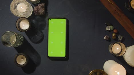 disparo aéreo de una persona que da lectura de tarot con pantalla verde teléfono móvil en la mesa